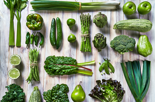 Table top view background of a variation green vegetables for detox and alkaline diet. Set on a white rustic table. Food knolling.