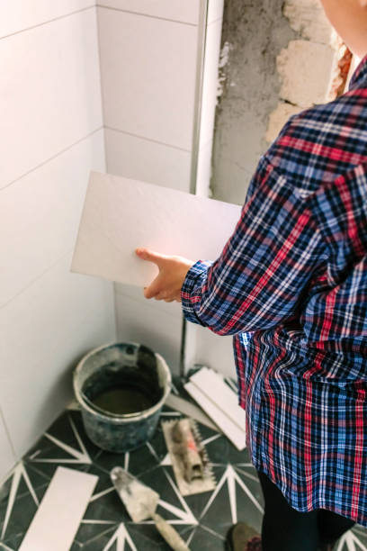 istock Female bricklayer taking a tile to bathroom renovation 1346707554