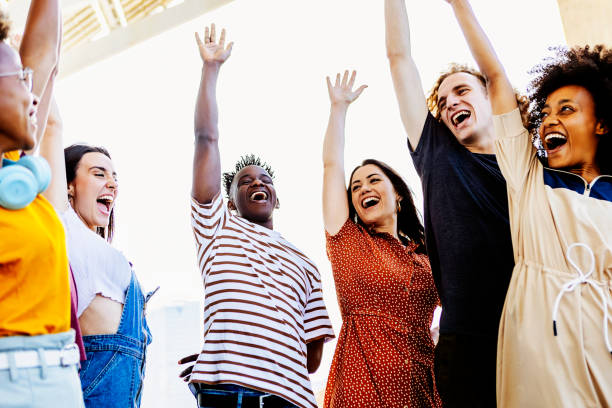 Group of young friends raising their hands in unity - Happy multiracial people having fun together and celebrating victory outdoors - Low angle view - Unity, integration and community concept - Focus on hispanic woman grupo de jóvenes amigos levantando la mano en unidad - felices personas multirraciales divirtiéndose juntas y celebrando la victoria al aire libre - vista de ángulo bajo - unidad, integración y concepto de comunidad - enfoque en la mujer hispana