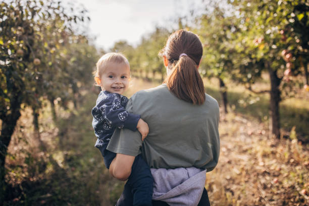 niño sonriente con mamá en el huerto - apple orchard child apple fruit fotografías e imágenes de stock