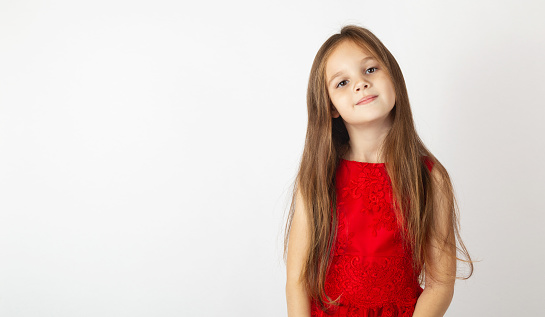 Beautiful child girl in an elegant red dress on a white background. Childhood. Children's fashion. Children holidays. Little Princess. copy space