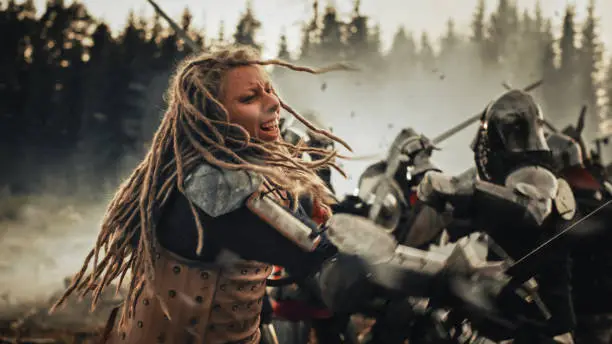 Epic Battlefield: Powerful Female Warrior Attacking, Fighting with Sword, Hitting Enemy with Deadly Blows. Dark Age Medieval Battle of Knight Soldiers. Cinematic Historic Reenactment.