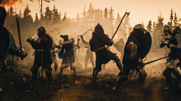 episches schlachtfeld: zwei gepanzerte mittelalterliche ritter, die mit schwertern kämpfen. dark ages army warfare. action schlacht von gepanzerten kriegersoldaten, töten von feinden. filmisches historisches reenactment. - battlefield stock-fotos und bilder