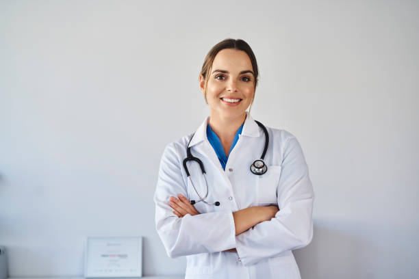 retrato de una doctora sonriente con uniforme de pie - doctora fotografías e imágenes de stock