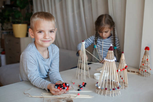 istock Kids make crafted Christmas tree from bamboo sticks, reusable ornament, DIY New Year decoration 1346713209