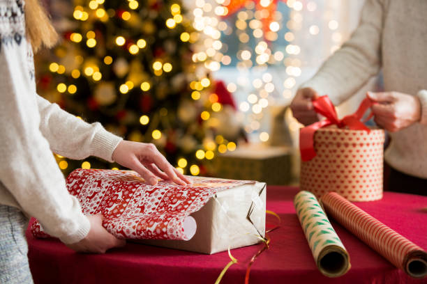 istock Couple in warm sweaters wrapping gifts 1346713375