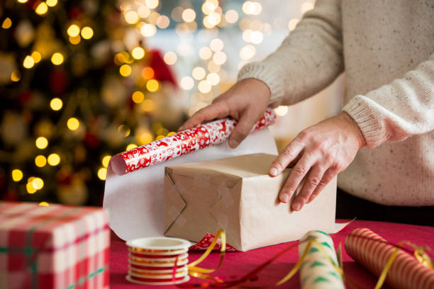 istock Couple in warm sweaters wrapping gifts 1346713394