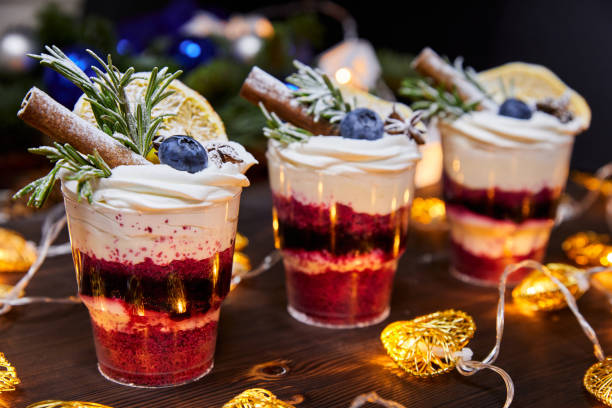 新鮮なブルーベリーとバニラスティックで飾られたデザートとしてカップのクリスマスのささいな、輝く花輪の背景にお祝いのテーブルのために