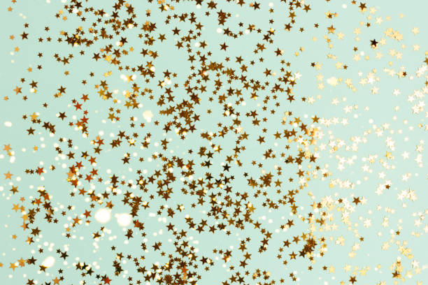 istock Glowing gold glittering stars confetti on a turquoise background. 1346714533