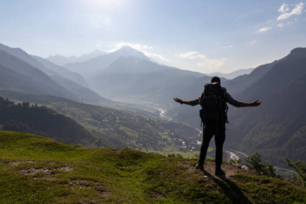istock Adishi - A man with big hiking backpack spreading his arms wide open, while standing on the mountain peak, overlooking Zardlashi 1346717526
