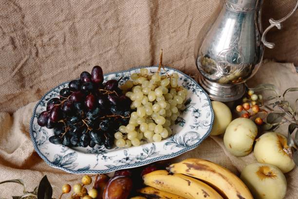 High angle view of red grapes, yellow carrots and pine nuts on cutting board, fresh ingredients to prepare a salad - preparing food and healthy lifestyle, copy space for text