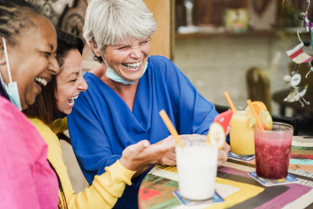 istock Happy multiracial senior woman using mobile phone at bar during coronavirus outbreak - Focus on right female face 1346718016