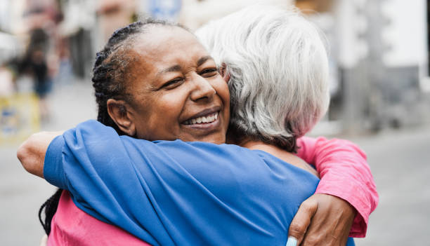 Senior multiracial women meeting and hugging each other outdoor stock photo