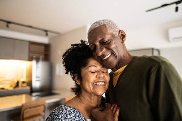 coppia anziana che si abbraccia a casa - 65 69 anni foto e immagini stock