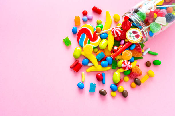 istock Glass jar spilling candies on pink background 1346720043