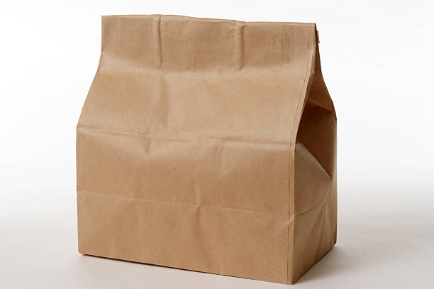 isolé photo de fermé brown sac en papier sur un arrière-plan blanc - blank paper bag packaging package photos et images de collection
