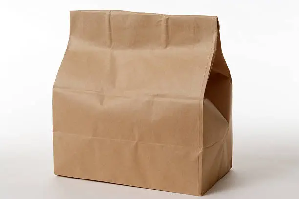 Photo of Isolated shot of closed brown paper bag on white background