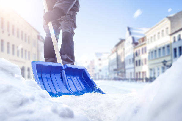 person, die im winter eine schneeschaufel auf einer straße benutzt - winterdienst stock-fotos und bilder