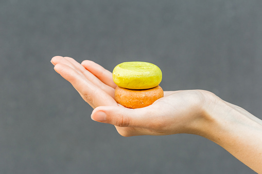 Woman hands holding organic soap or solid shampoo with no packaging over gray background. Healthy lifestyle, beauty, skin care, Zero waste concept.