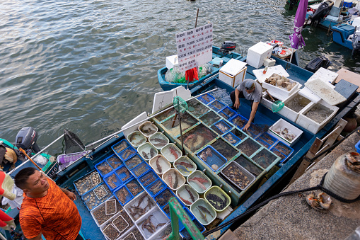 Hong Kong - October 3, 2021 : Fishermen doing business at a floating seafood market in Sai Kung Pier, New Territories, Hong Kong. It is famous for its seafood market and restaurants in the fishing village, Hong Kong.