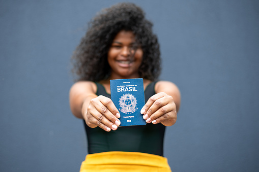 Translation: 'Federative Republic of Brazil, Ministry of Labour'. Brazilian notebook. Concept of FGTS, unemployment, salary and Brazilian economy. Hand holding (Carteira de Trabalho brasileira).