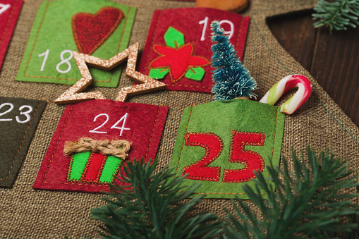 Christmas calendar with gifts for children. Textile Xmas advent calendar on dark wooden background. Festive winter holiday card, copy space.