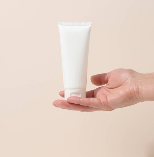 istock female hand holds empty white plastic tubes for cosmetics. Packaging for cream, gel, serum, advertising and product promotion, mock up 1346732764