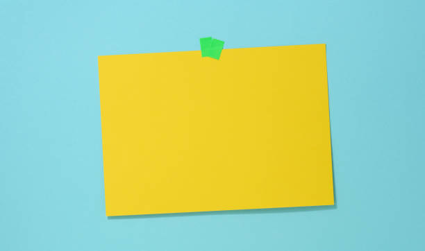 istock blank rectangular yellow sheet of paper glued on a blue background. Place for an inscription, announcement 1346733731