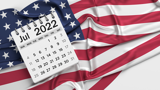 White-colored July calendar page and the American flag. Horizontal composition with copy space. Isolated with clipping path.