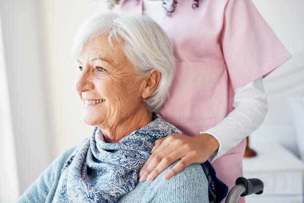 Cropped shot of an attractive senior woman looking thoughtful while sitting with a nurse in her room at the retirement home stock photo
