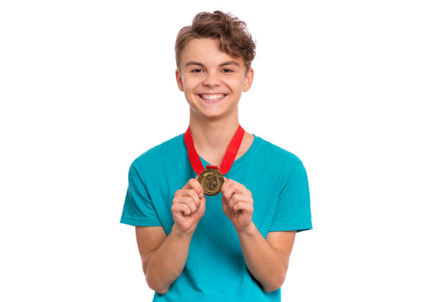 Happy winner. Portrait of Handsome Teen Boy Student holding gold Medal. Smiling child celebrating his success, isolated on white background. Back to School or sport concept