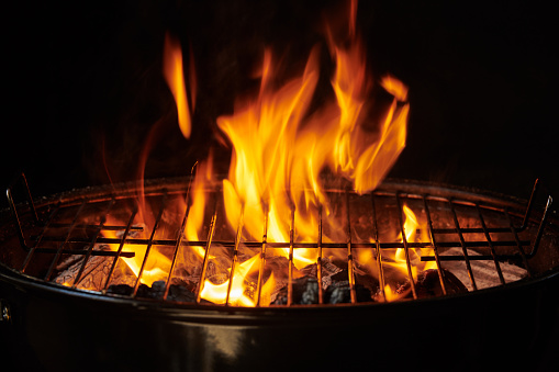 Close-up photo of blazing hot charcoal underneath a wire grid of a barbecue grill.