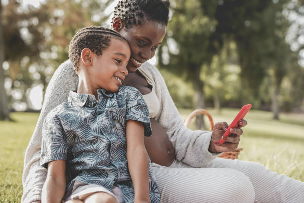 istock African mother and mixed race son using mobile phone at park 1346746877