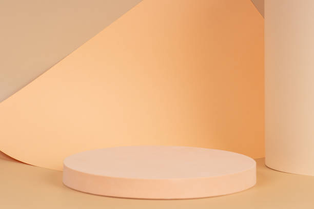 istock Abstract trendy composition with empty round podium platform for product presentation and curve shaped paper on pastel beige background. Front view 1346751180