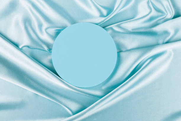 Geometric platform podium on light blue silk satin background. Blank minimal cylinder form mock up background for cosmetic product presentation Geometric platform podium on light blue silk satin background. Blank minimal cylinder form mock up background for cosmetic product presentation. light blue silk stock pictures, royalty-free photos & images