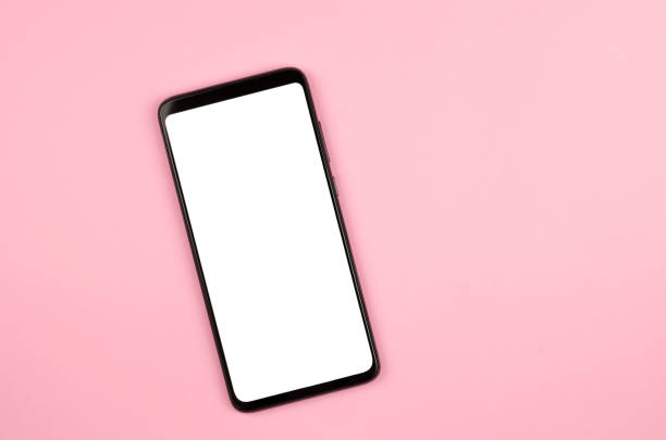 istock Smartphone with a white display on a pink background. Mock up mobile phone flat lay 1346754839