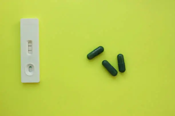 Photo of positive pregnancy test and pills on a yellow background. Vitamins. Motherhood, children, pregnancy, the concept of birth control. Health problems and problems with conception. abortion. contraception