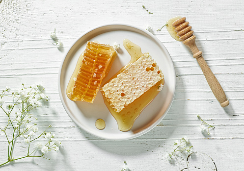plate of fresh honey combs on white wooden table, top view