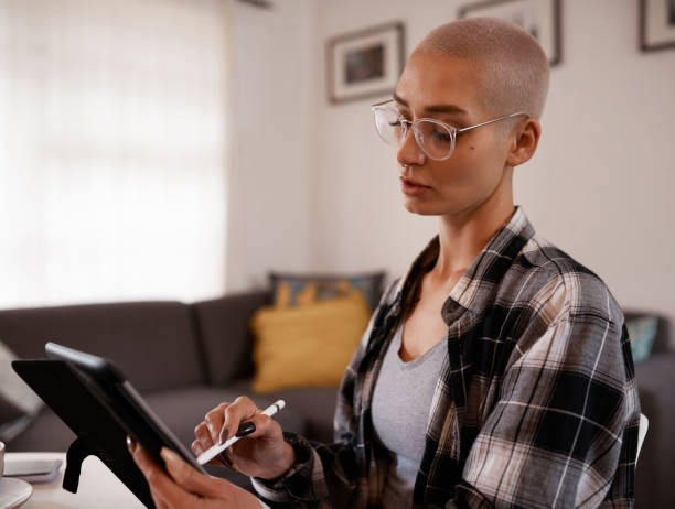 istock Shot of a young woman using a digital tablet while sitting at home 1346762737