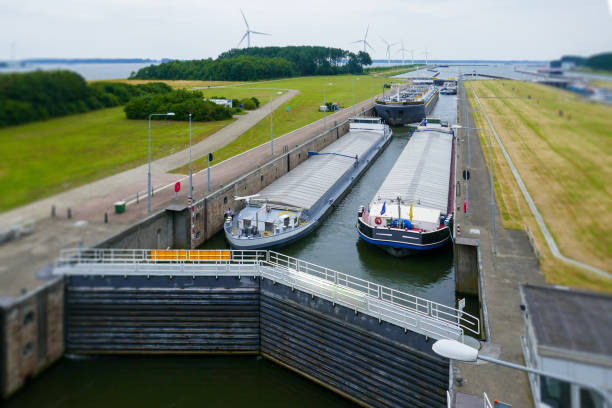 two inland barge (ship) on the long straight canal just waiting in ship lock south of rotterdam close to numansdorp. summer day with wind turbines behind - lock stok fotoğraflar ve resimler