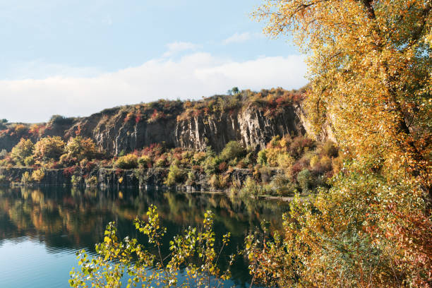 Golden autumn with colourful trees in old flooded quarry. Rocks, lake and yellow trees