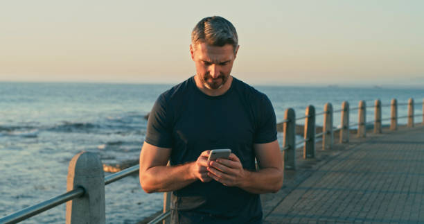 istock Shot of a mature man using a cellphone while exercising along the promenade 1346775156