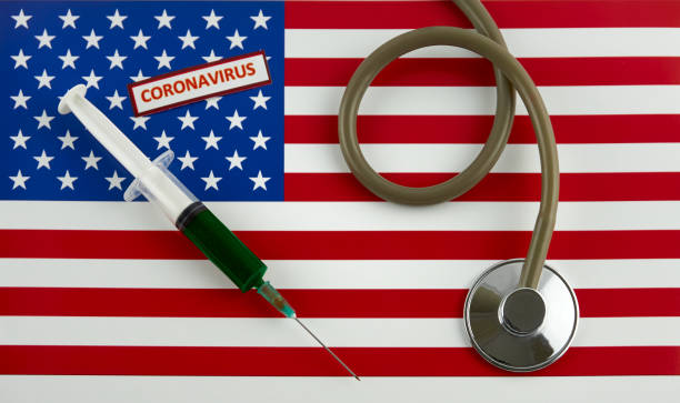 istock Stethoscope and syringe on USA flag with coronavirus label 1346779332
