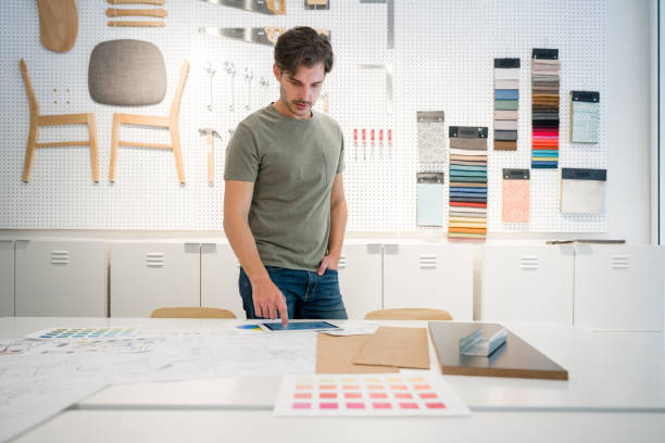 Interior designer looking at pictures on his tablet at the office