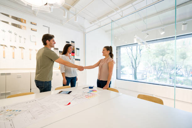 Happy interior designer greeting clients at the office with a handshake