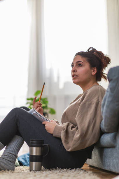 istock Young woman contemplating the solution to math homework she is writing 1346783453