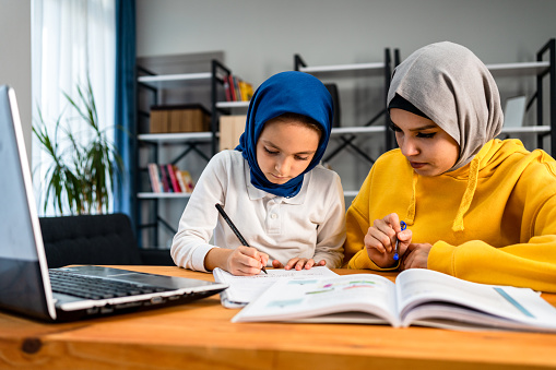Muslim girl helping her sister with homework