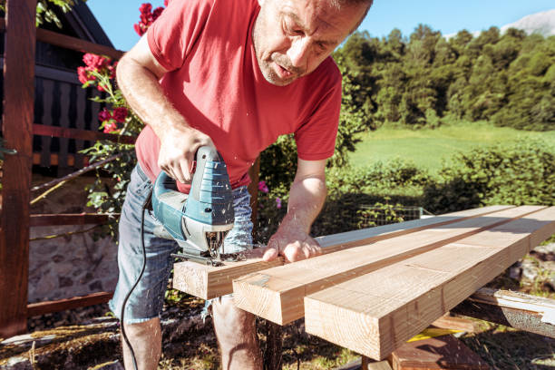 istock Man Sawing Raw Wooden Fence Board Using Electric Jigsaw 1346784985