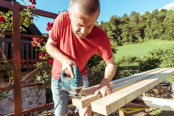 istock Man Sawing Raw Wooden Fence Board Using Electric Jigsaw 1346784988