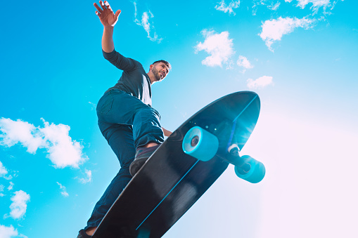 Skateboarder in action. Man riding on a surf skate outdoors on sunny summer day. Blue sky background. . High quality photo